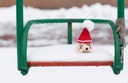 Winter holidays background:  small plush dog in Santa hat on a snowy swing. Closeupの写真素材
