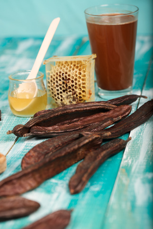 Carob pods and powder on a wooden surface. Closeup