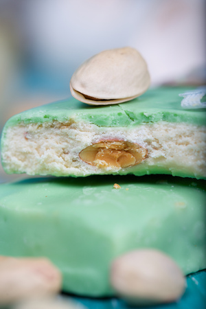 Almond turron covered by pistachio chocolate on a wooden surface. Closeupの写真素材