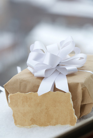 Present in kraft paper wrapping in the snow. Closeupの写真素材