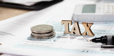 Word TAX composed of wooden letters. Coins, papers, pen in the background. Closeupの写真素材