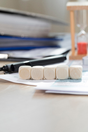Five wooden dices. Money, papers, pen in the background. Closeupの写真素材