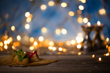 Arabic sweets on a wooden surface. Candle holders, night light and night blue sky with crescent moon in the background.の写真素材