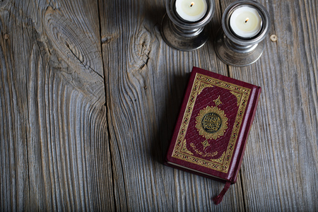 Quran and candles on a wooden surface. Translation into English - the book contains verses of Koranの写真素材