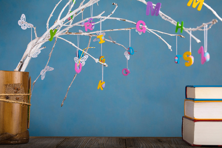 Colorful letters on tree twigs. Blue background  Colorful letters on tree twigs.  Thick books in the...