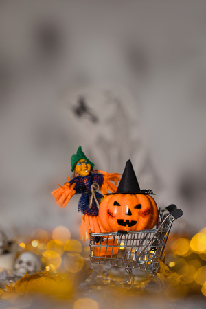 Witch and orange pumpkin in black hat in the small shopping cart. Spooky background. Closeupの写真素材