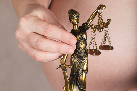Young pregnant between 30 and 35 years old woman keeps statue of Themis. Closeupの写真素材
