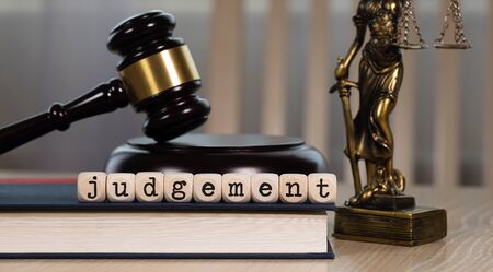 Word  JUDGEMENT composed of wooden dices. Wooden gavel and statue of Themis in the background. Closeupの写真素材