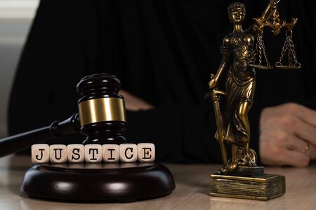 Word JUSTICE composed of wooden dices. Wooden gavel and statue of Themis in the background. Closeupの写真素材