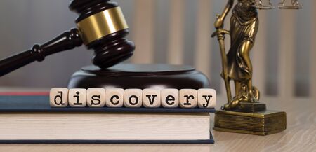 Word DISCOVERY composed of wooden dices. Wooden gavel and statue of Themis in the background. Closeupの写真素材