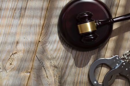 Wooden gavel and handcuff on a wooden surface. Closeupの写真素材