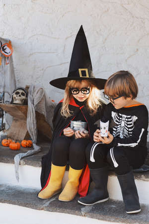 Kids in Halloween costumes are sitting on the porchの写真素材