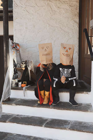 Kids in Halloween costumes are sitting on the porch