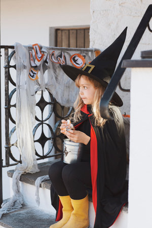 Girl in Halloween costume is sitting on the porchの写真素材