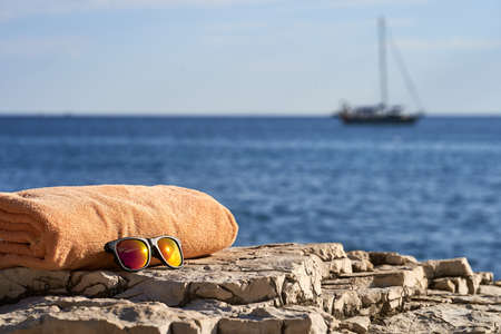 orange towel and sunglasses laying on a rock near to Istrian seaの写真素材