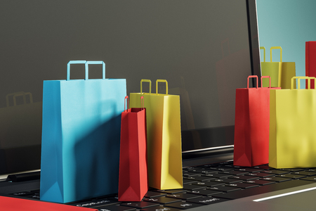Empty laptop with tiny shopping bags on blue background. Online shopping and shop concept. Mock up, 3D Rendering の写真素材