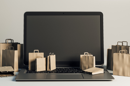 Empty laptop with tiny shopping bags on gray background. Online shopping and mobile concept. Mock up, 3D Rendering の写真素材