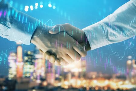 Double exposure of financial chart on cityscape background with two businessmen handshake. Concept of financial analysis and investment opportunitiesの写真素材