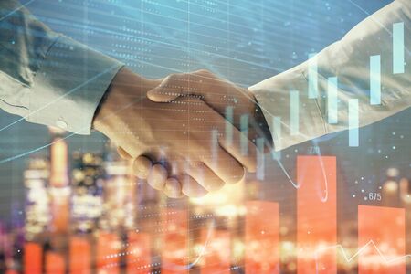 Double exposure of financial chart on cityscape background with two businessmen handshake. Concept of financial analysis and investment opportunitiesの写真素材