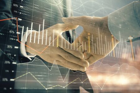 Double exposure of financial chart on cityscape background with two businessmen handshake. Concept of financial analysis and investment opportunitiesの写真素材