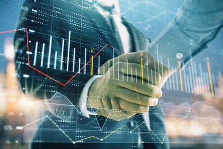 Double exposure of financial chart on cityscape background with two businessmen handshake. Concept of financial analysis and investment opportunitiesの写真素材