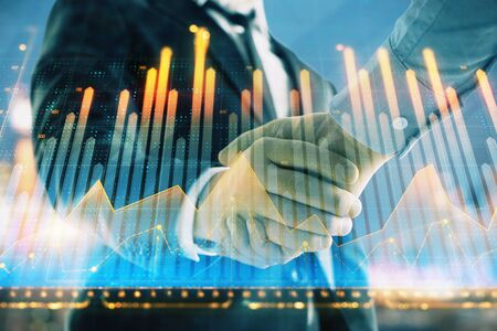 Double exposure of financial chart on cityscape background with two businessmen handshake. Concept of financial analysis and investment opportunitiesの写真素材