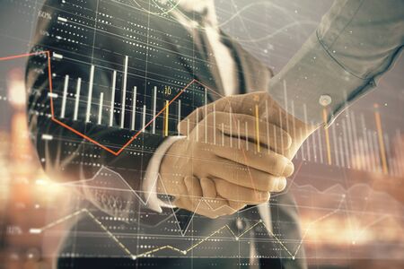Double exposure of financial chart on cityscape background with two businessmen handshake. Concept of financial analysis and investment opportunitiesの写真素材