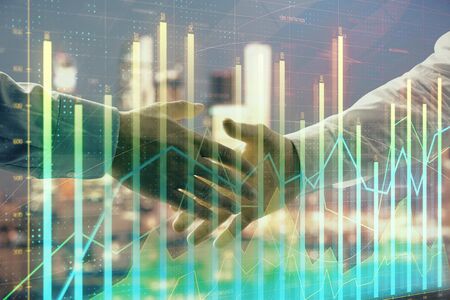 Double exposure of financial chart on cityscape background with two businessmen handshake. Concept of financial analysis and investment opportunitiesの写真素材