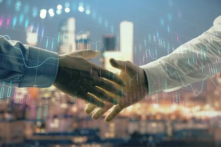 Double exposure of financial chart on cityscape background with two businessmen handshake. Concept of financial analysis and investment opportunitiesの写真素材