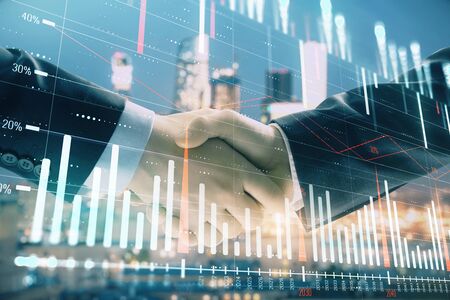 Double exposure of financial graph on cityscape background with two businessman handshake. Concept of stock market dealの写真素材