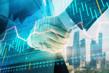 Double exposure of financial graph on cityscape background with two businessman handshake. Concept of stock market dealの写真素材