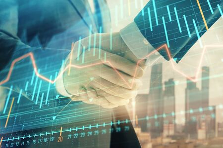 Double exposure of financial graph on cityscape background with two businessman handshake. Concept of stock market dealの写真素材