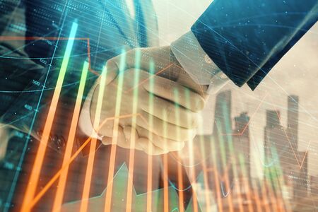Double exposure of financial graph on cityscape background with two businessman handshake. Concept of stock market dealの写真素材