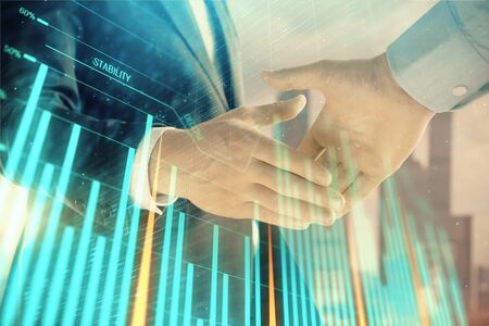 Double exposure of financial graph on cityscape background with two businessman handshake. Concept of stock market dealの写真素材