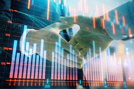Double exposure of financial graph on cityscape background with two businessman handshake. Concept of stock market dealの写真素材