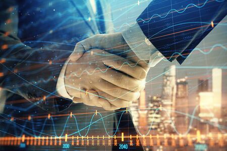 Double exposure of financial chart on cityscape background with two businessmen handshake. Concept of financial analysis and investment opportunitiesの写真素材