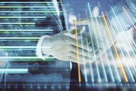 Double exposure of financial chart on cityscape background with two businessmen handshake. Concept of financial analysis and investment opportunitiesの写真素材