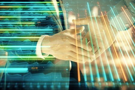 Double exposure of financial chart on cityscape background with two businessmen handshake. Concept of financial analysis and investment opportunitiesの写真素材