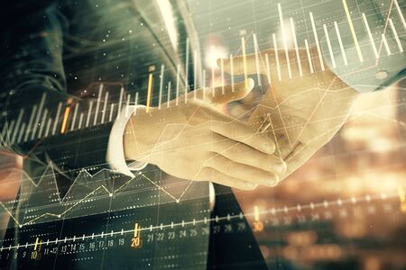 Double exposure of financial chart on cityscape background with two businessmen handshake. Concept of financial analysis and investment opportunitiesの写真素材