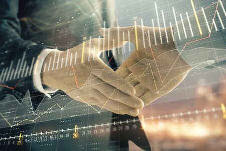 Double exposure of financial chart on cityscape background with two businessmen handshake. Concept of financial analysis and investment opportunitiesの写真素材