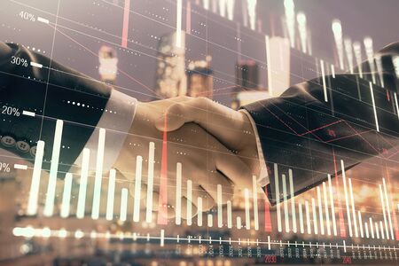 Double exposure of financial graph on cityscape background with two businessman handshake. Concept of stock market dealの写真素材