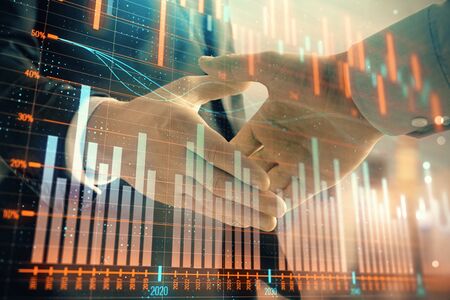 Double exposure of financial graph on cityscape background with two businessman handshake. Concept of stock market dealの写真素材