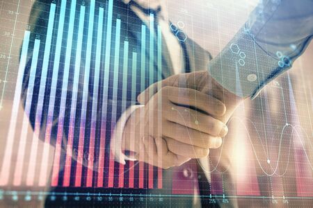 Double exposure of financial graph on cityscape background with two businessman handshake. Concept of stock market dealの写真素材