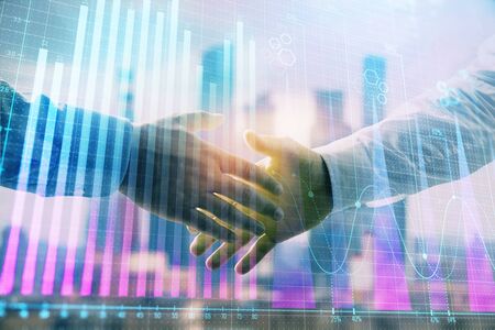 Double exposure of financial graph on cityscape background with two businessman handshake. Concept of stock market dealの写真素材
