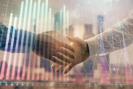 Double exposure of financial graph on cityscape background with two businessman handshake. Concept of stock market dealの写真素材