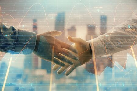Double exposure of financial graph on cityscape background with two businessman handshake. Concept of stock market dealの写真素材