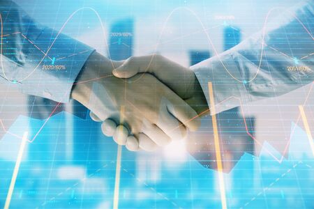 Double exposure of financial graph on cityscape background with two businessman handshake. Concept of stock market dealの写真素材