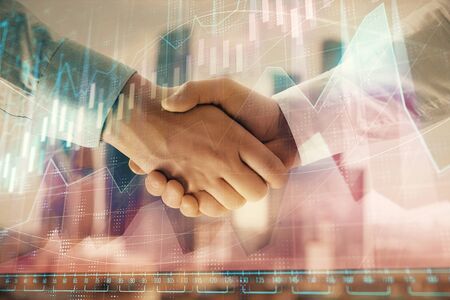 Double exposure of financial graph on cityscape background with two businessman handshake. Concept of stock market dealの写真素材
