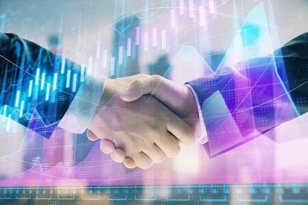 Double exposure of financial graph on cityscape background with two businessman handshake. Concept of stock market dealの写真素材