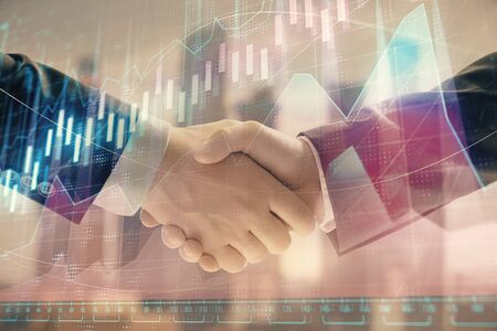 Double exposure of financial graph on cityscape background with two businessman handshake. Concept of stock market dealの写真素材